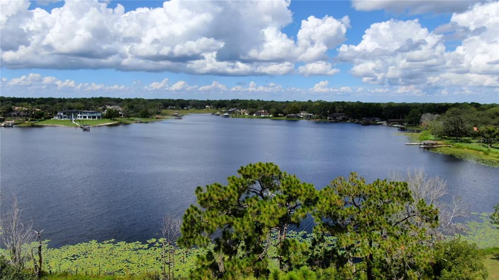 An aerial view shows a large lake surrounded by trees and residential homes — LAKE MARKHAM ROAD, SANFORD, FL
