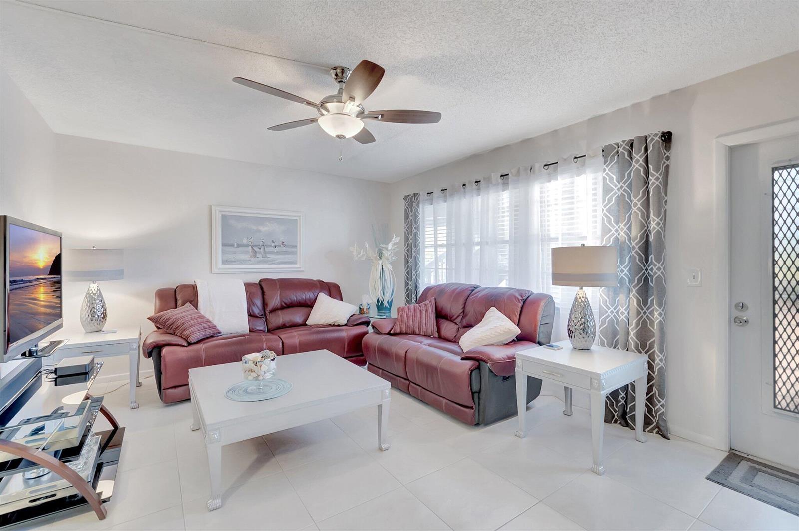 A living room features two burgundy leather sofas, a white coffee table, and tile flooring — 2051 Cambridge C, Deerfield Beach FL 33442, DEERFIELD BEACH, FL