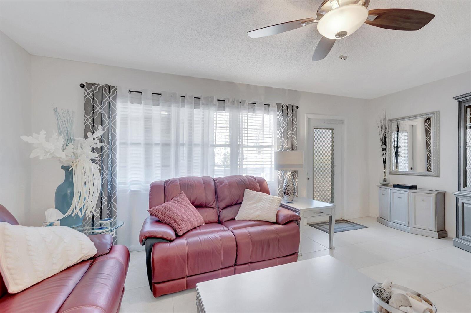 A living room features red leather sofas, white tile floors, and a ceiling fan — 2051 Cambridge C, Deerfield Beach FL 33442, DEERFIELD BEACH, FL