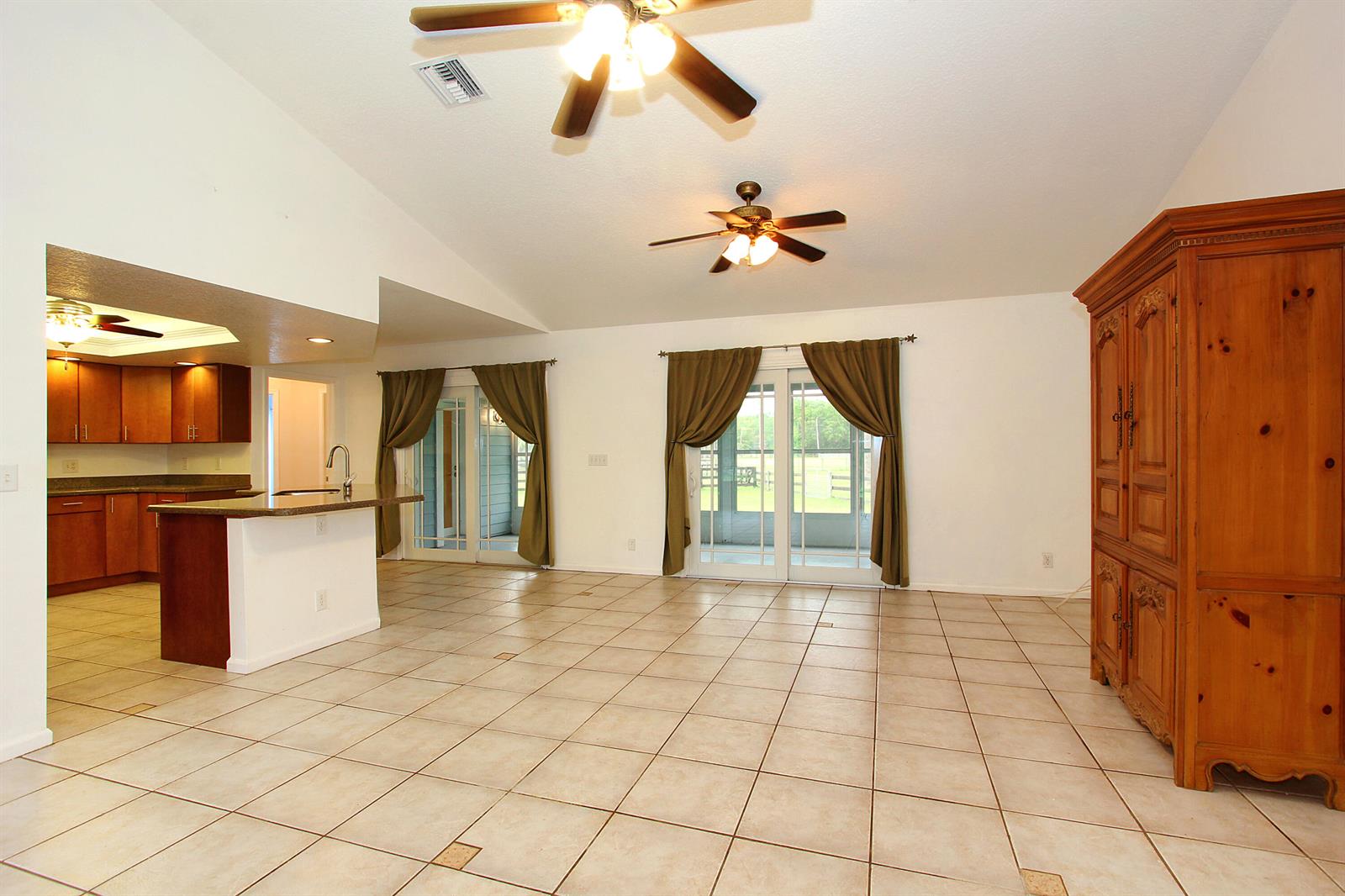 A spacious living area with tile floors, two ceiling fans, and sliding glass patio doors — 16655 N 113th Trl Trail N, Jupiter FL 33478, JUPITER, FL