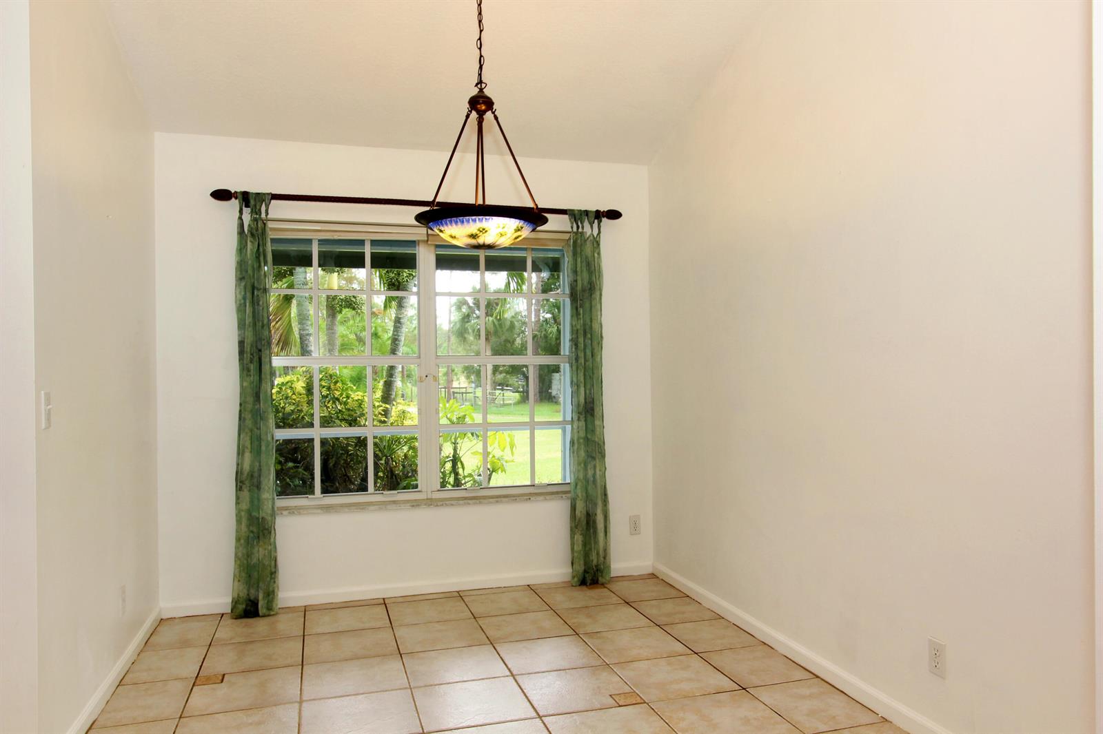 An empty dining area features tile flooring, a hanging light fixture, and a large window — 16655 N 113th Trl Trail N, Jupiter FL 33478, JUPITER, FL
