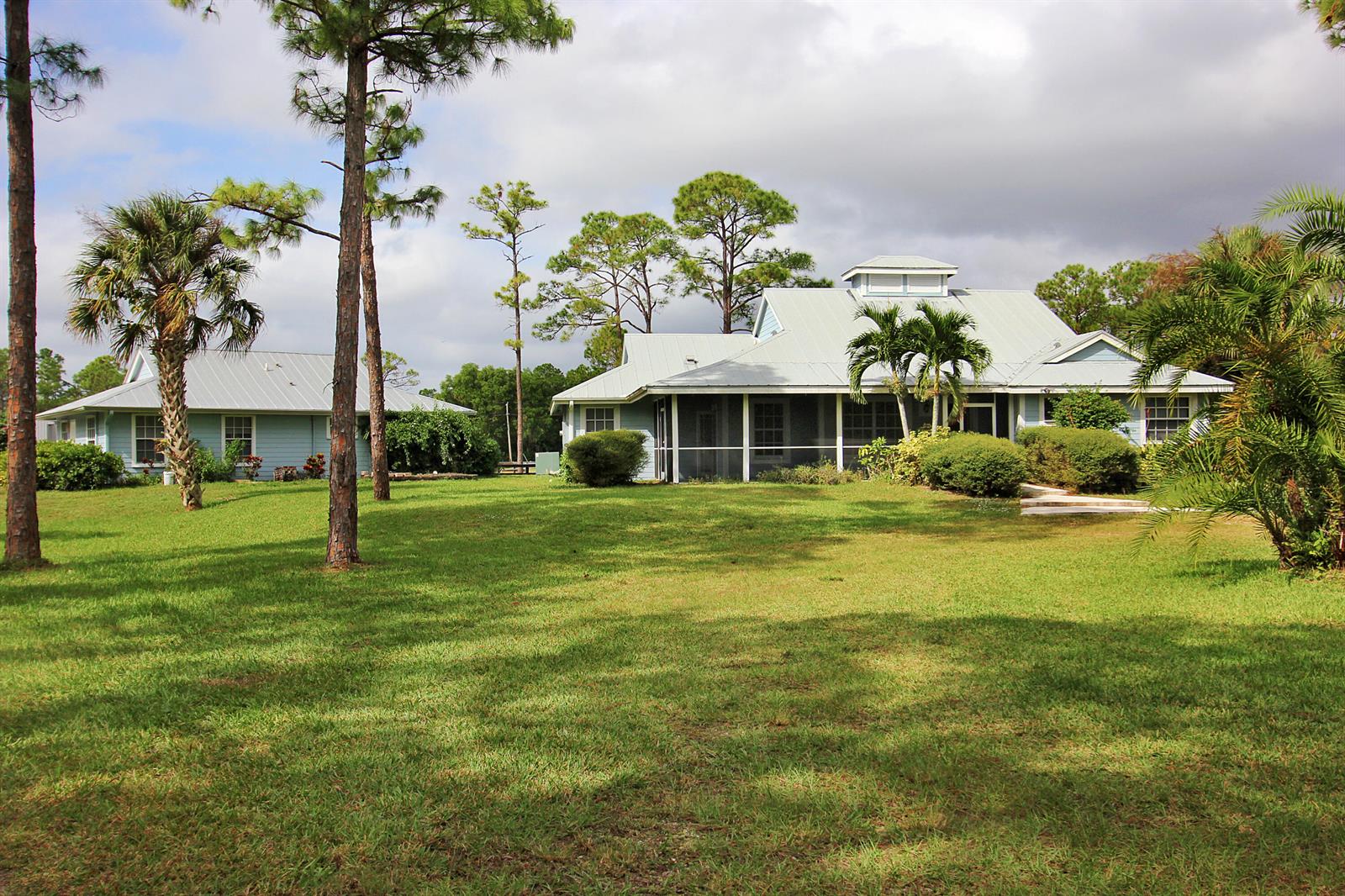 A light blue house with a metal roof and a screened porch sits on grass — 16655 N 113th Trl Trail N, Jupiter FL 33478, JUPITER, FL
