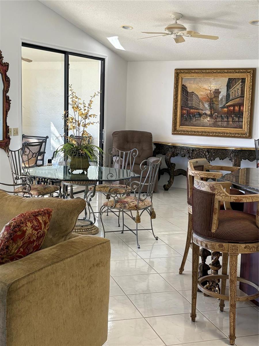 A dining area with a glass table, metal chairs, and a large framed painting on wall — 7744 Dundee Lane, Delray Beach FL 33446, DELRAY BEACH, FL