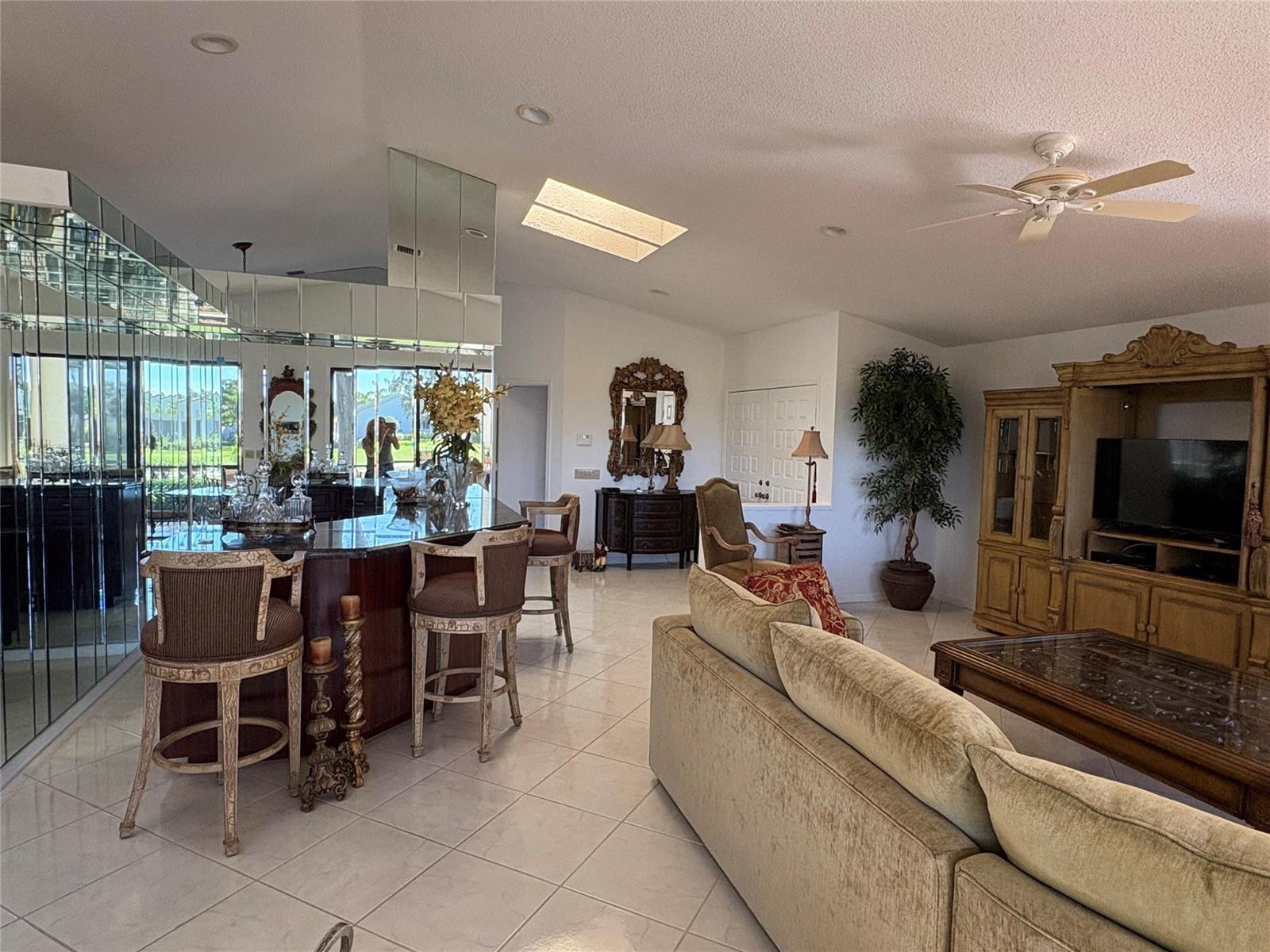 A living room and kitchen area with a mirrored bar, tile flooring, and traditional furniture — 7744 Dundee Lane, Delray Beach FL 33446, DELRAY BEACH, FL