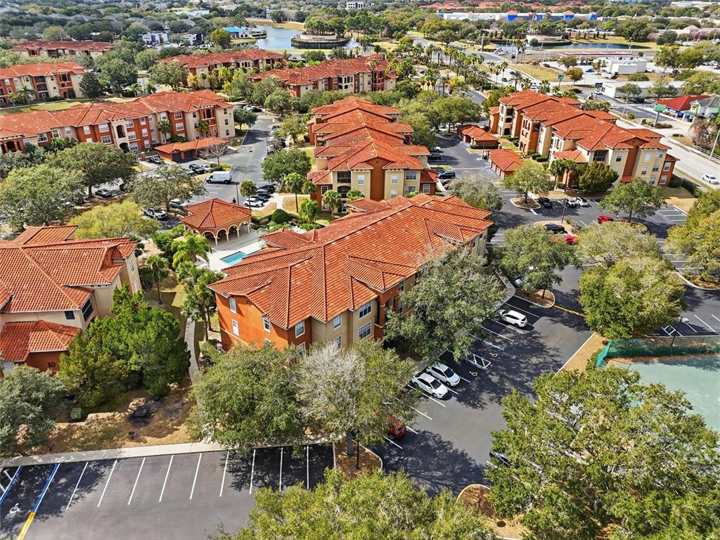 An aerial view of a multi-story apartment complex with red tile roofs and parking lots — 5518 METROWEST BOULEVARD UNIT 11-104, ORLANDO, FL