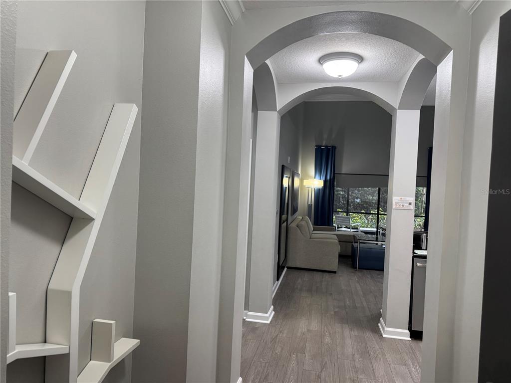 A hallway with a white decorative wall shelf leads into a living area with flooring — 14501 GROVE RESORT AVENUE UNIT 1110, WINTER GARDEN, FL