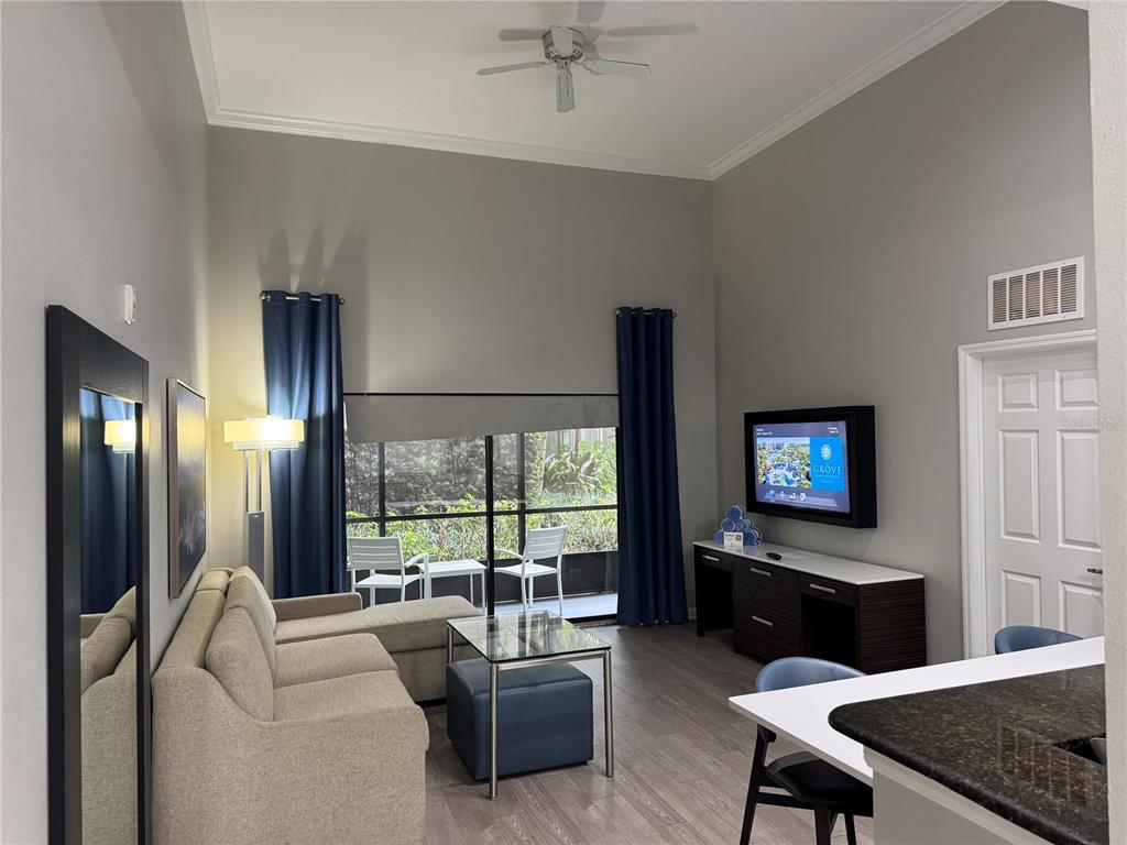 A living room features a sofa, glass coffee table, television, and a sliding glass door — 14501 GROVE RESORT AVENUE UNIT 1110, WINTER GARDEN, FL