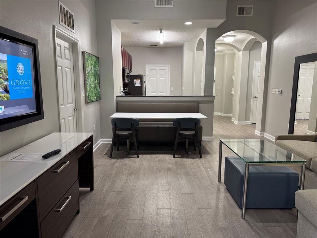 A living room area features a dining booth, a desk, and a glass-topped coffee table — 14501 GROVE RESORT AVENUE UNIT 1110, WINTER GARDEN, FL