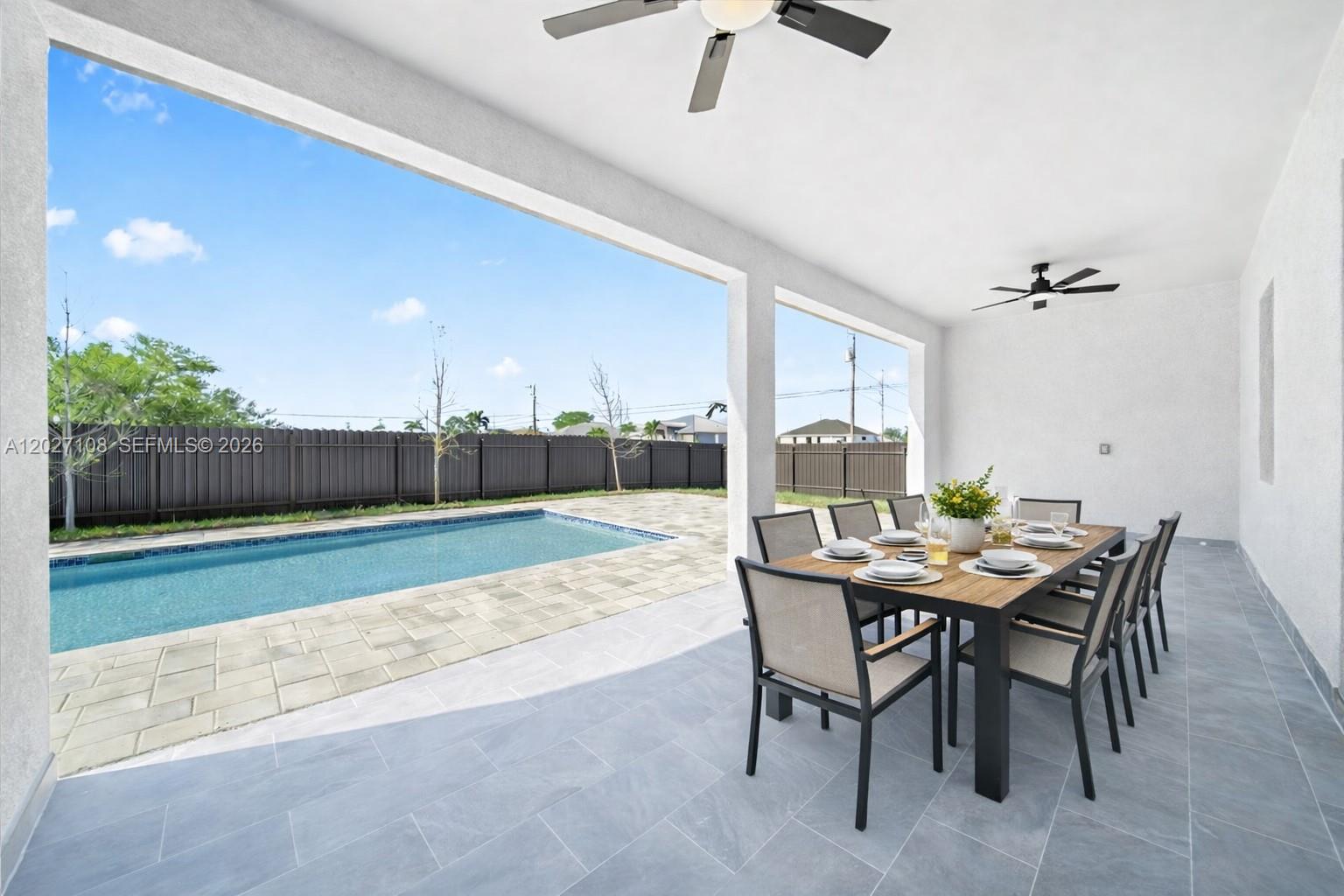 A covered patio features a dining set, ceiling fans, and a view of a swimming pool — 1226 NE 5TH PL, Cape Coral FL 33909, CAPE CORAL, FL