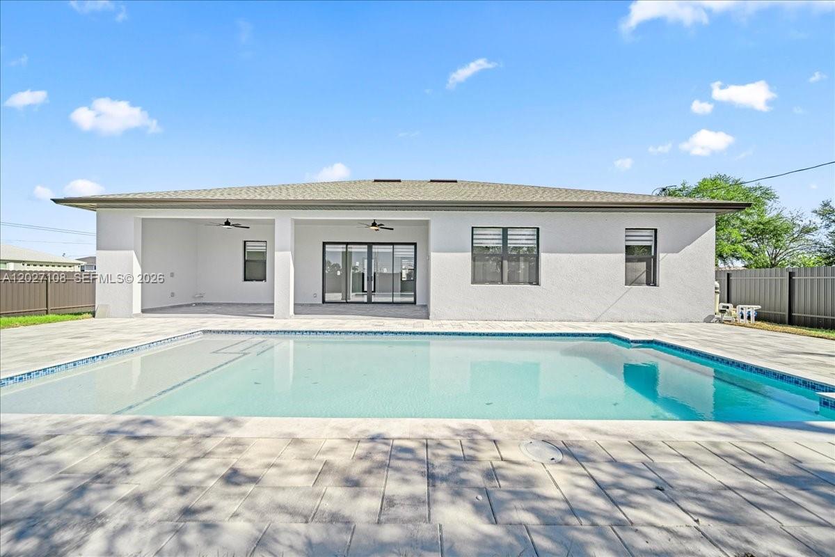 A view of the back of a house with a covered patio and swimming pool — 1226 NE 5TH PL, Cape Coral FL 33909, CAPE CORAL, FL