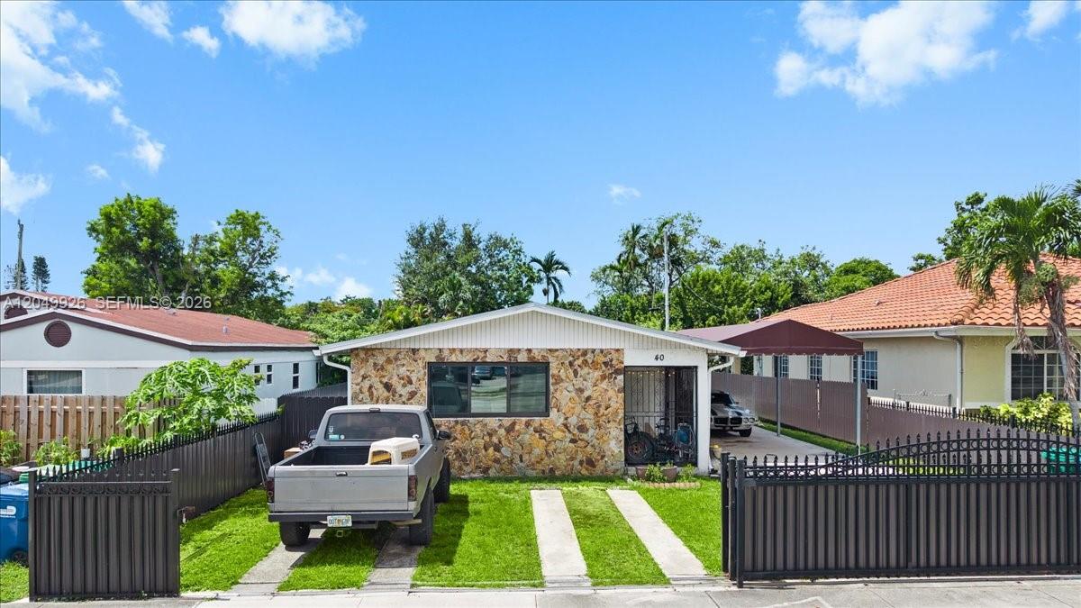 A single-story house with a stone facade, a driveway, and a gated front yard — 40 NW 119th St, Miami FL 33168, MIAMI, FL