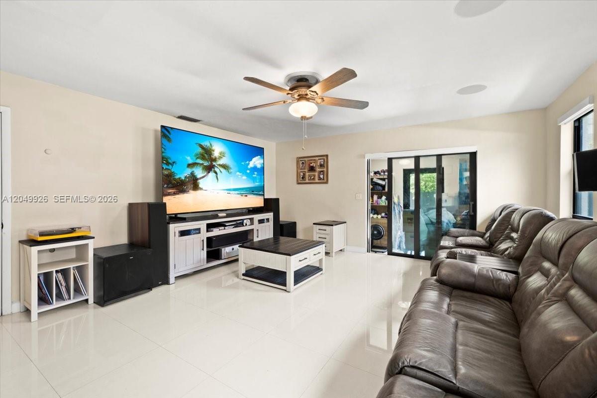 A living room features a large television, a brown leather sofa, and tile flooring — 40 NW 119th St, Miami FL 33168, MIAMI, FL