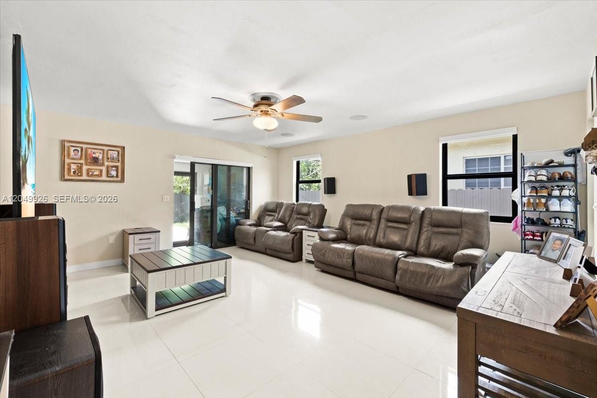 A living room features light-colored tile floors, leather furniture, and a ceiling fan — 40 NW 119th St, Miami FL 33168, MIAMI, FL