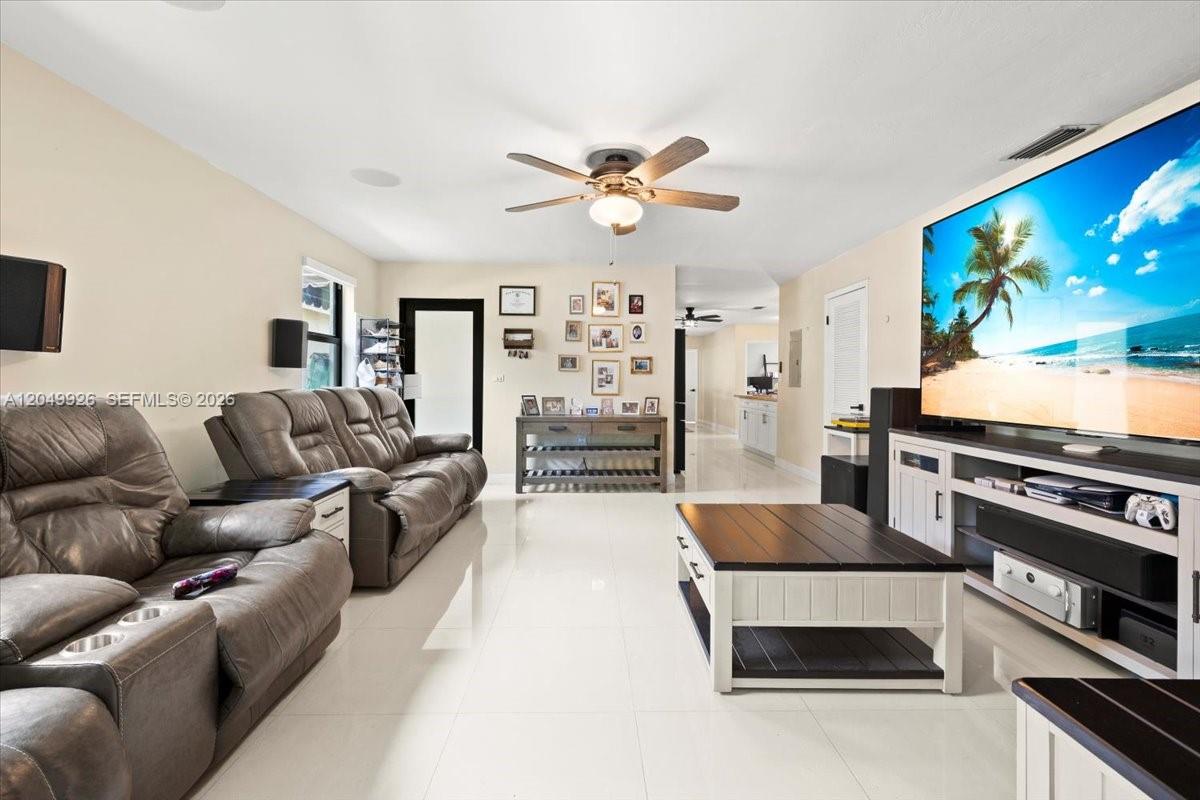 A living room features light tile floors, a large television, and a leather sofa — 40 NW 119th St, Miami FL 33168, MIAMI, FL