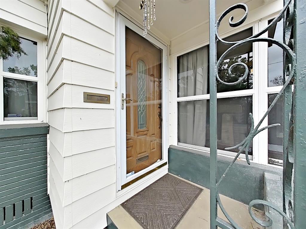 A front entrance features a white storm door, a brown wood door, and metal railings — 235 38TH STREET S, ST PETERSBURG, FL