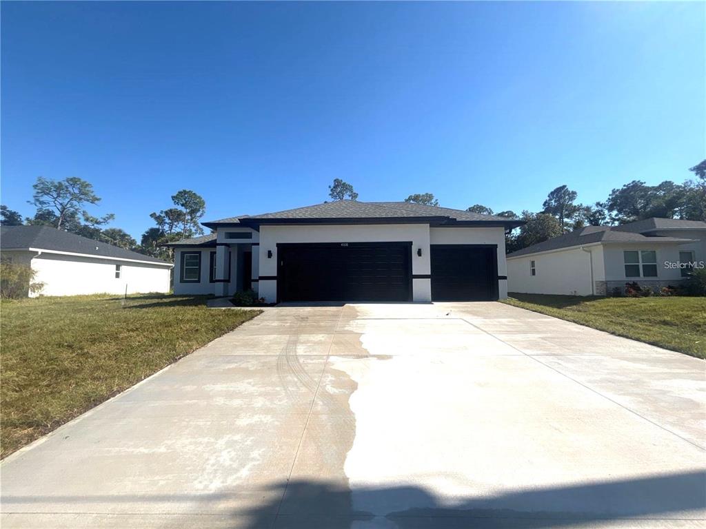 A single-story house with a white exterior, black trim, and a three-car garage — 3068 VELVET LANE, NORTH PORT, FL