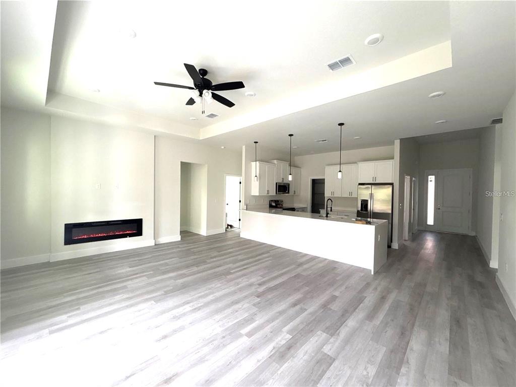 An open-concept living room and kitchen feature light wood flooring, a fireplace, and white cabinetry — 3068 VELVET LANE, NORTH PORT, FL