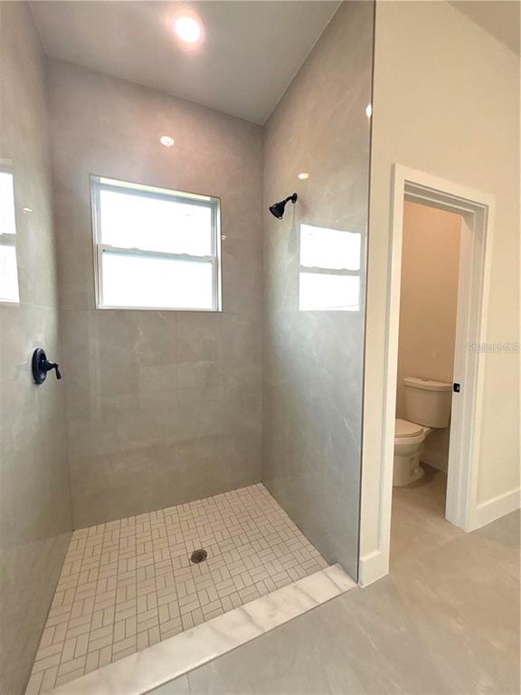 A walk-in shower with light-colored tile walls and a separate toilet room — 3068 VELVET LANE, NORTH PORT, FL