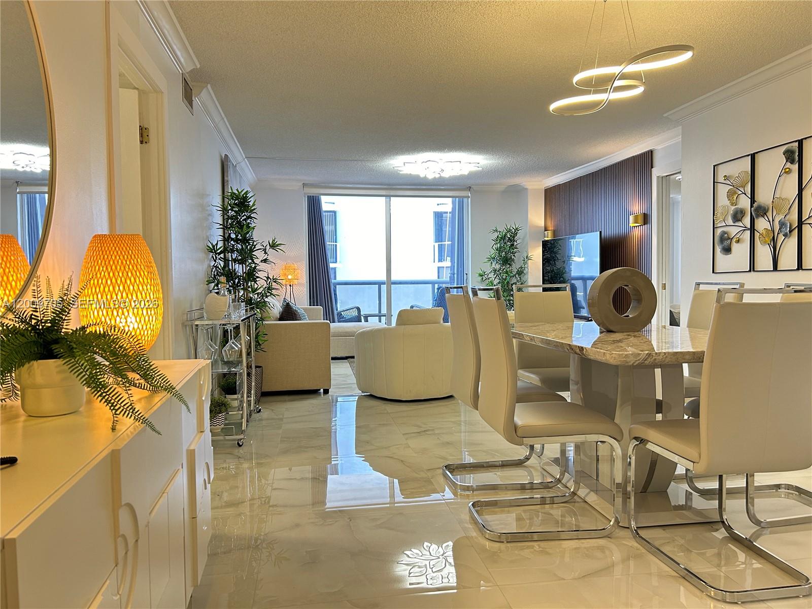 A modern dining and living area features marble floors, a slatted wood wall, and balcony access — 6039 Collins Ave # 1507, Miami Beach FL 33140, MIAMI BEACH, FL