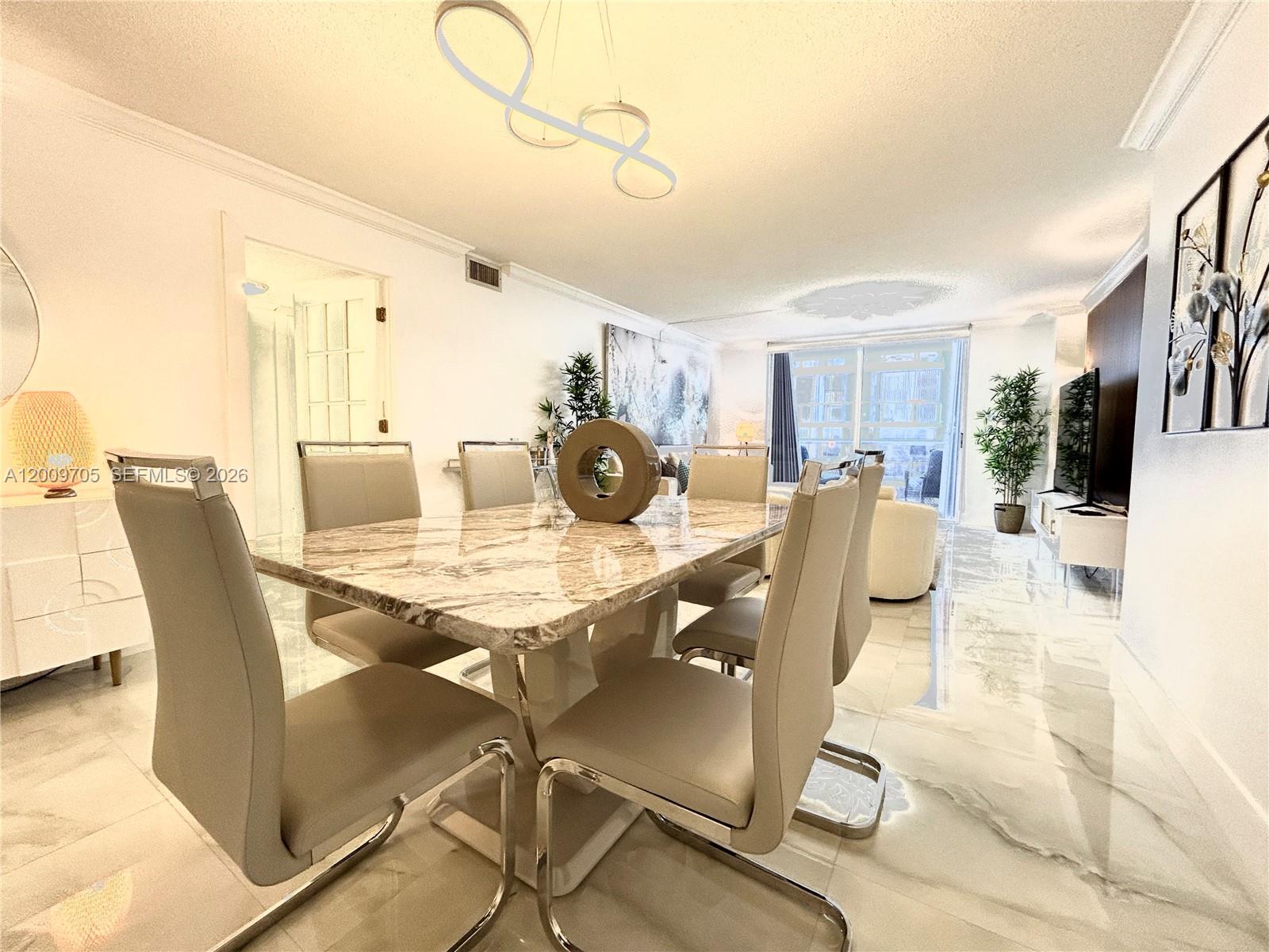 A dining room features a marble table, modern chairs, and white tile flooring — 6039 Collins Ave # 1507, Miami Beach FL 33140, MIAMI BEACH, FL