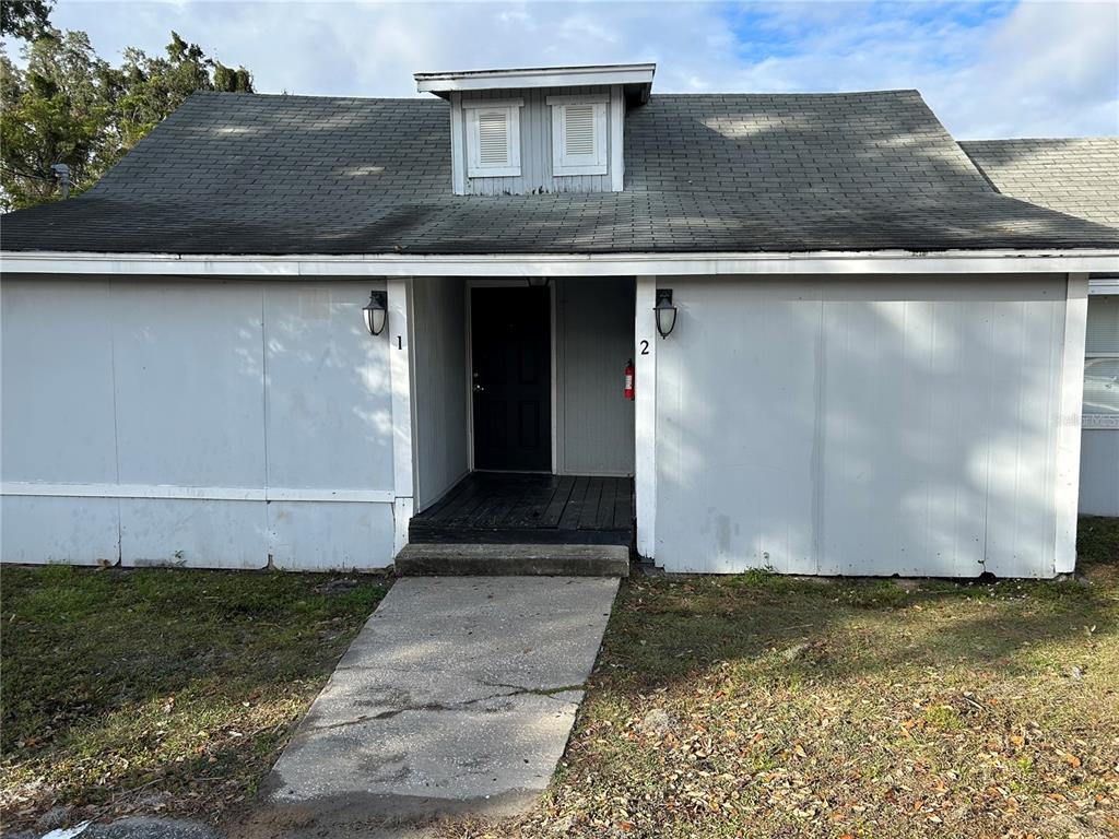 A single-story building with gray siding, a dark roof, and a central recessed entryway — 6015 FOREST CITY ROAD, ORLANDO, FL
