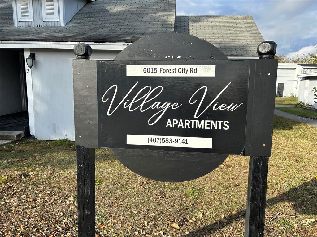 A black sign for Village View Apartments stands in front of a residential building — 6015 FOREST CITY ROAD, ORLANDO, FL