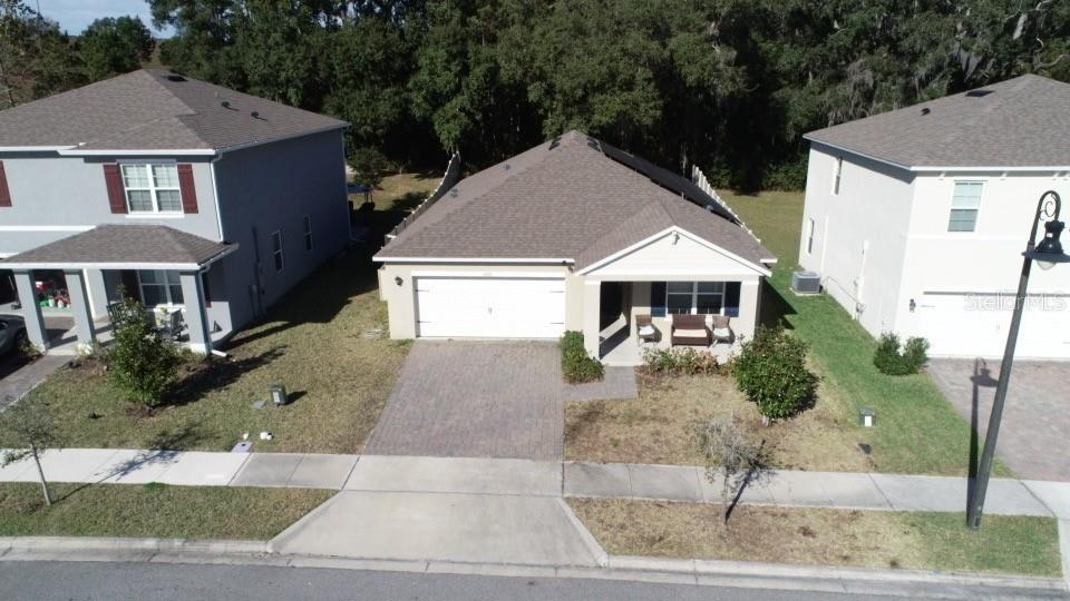 An aerial view shows a single-story house with a paved driveway between two-story homes — 5696 GALLOPING DRIVE, APOPKA, FL