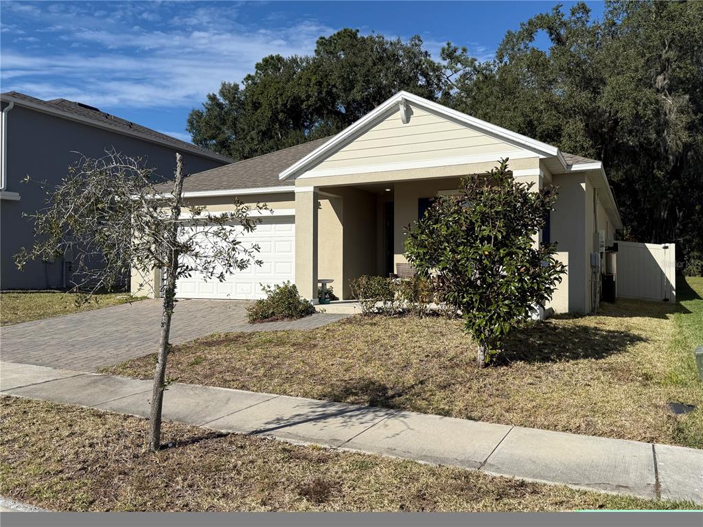 A single-story tan house with a paved driveway, a garage, and a front porch — 5696 GALLOPING DRIVE, APOPKA, FL