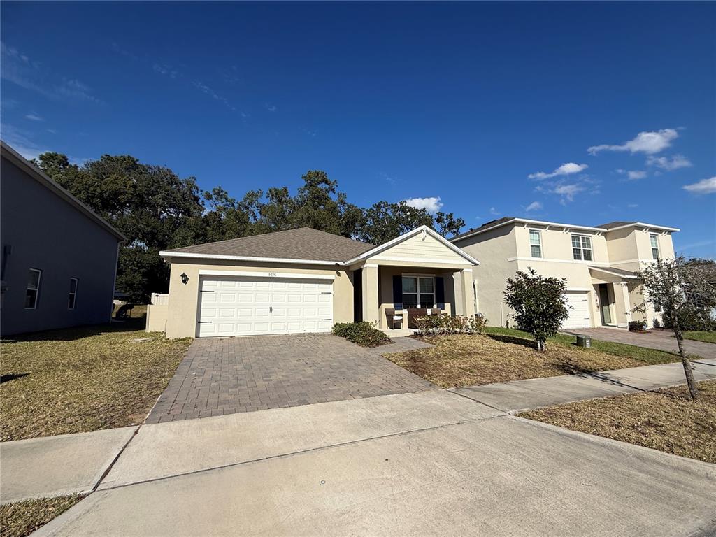 A single-story house with a beige exterior, a two-car garage, and a covered front porch — 5696 GALLOPING DRIVE, APOPKA, FL