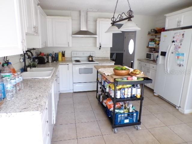 A kitchen features white cabinets, granite countertops, a stainless steel range, and a rolling cart — 5766 FORESTER PINE COURT, SARASOTA, FL