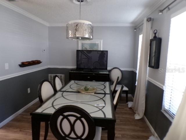 A dining room features a glass-topped table, six chairs, a television, and two-toned walls — 5766 FORESTER PINE COURT, SARASOTA, FL