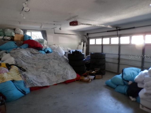 A cluttered garage features a large pile of items covered by a sheet and stacked tires — 5766 FORESTER PINE COURT, SARASOTA, FL