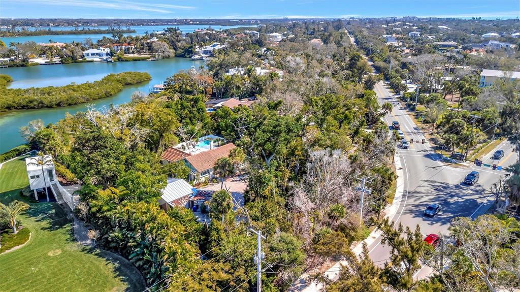 An aerial view shows a coastal property with a house, lush trees, and a road — 4237 HIGEL AVENUE, SARASOTA, FL