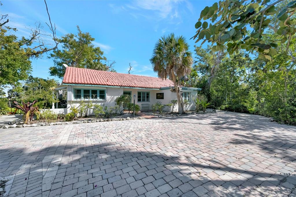 A single-story house with a red tile roof sits behind a large paved driveway — 4237 HIGEL AVENUE, SARASOTA, FL