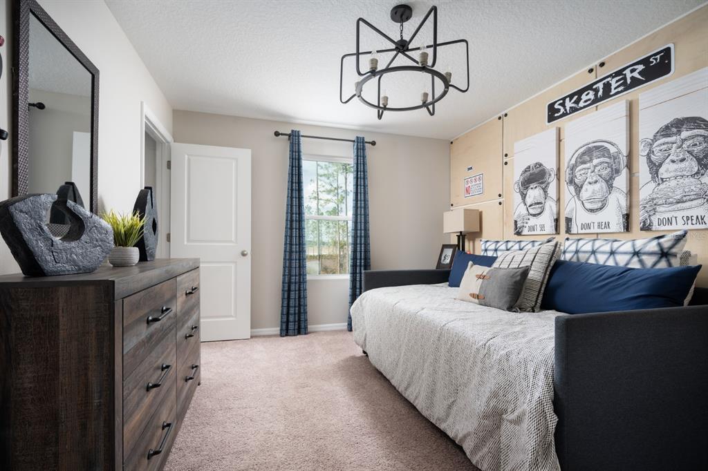 A bedroom features a daybed, a wooden dresser, a modern chandelier, and monkey-themed wall art — 9284 JOYFUL HEIGHTS WAY, DADE CITY, FL