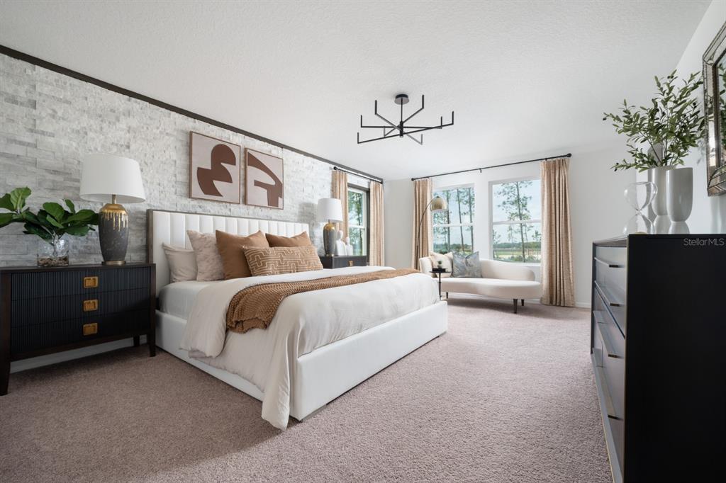 A bedroom features a white upholstered bed, stone accent wall, and black furniture — 9284 JOYFUL HEIGHTS WAY, DADE CITY, FL