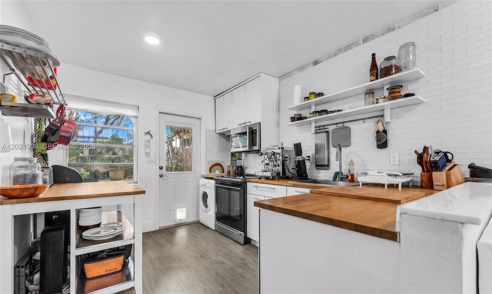 A kitchen features white cabinets, butcher block countertops, open shelving, and a white brick backsplash — 645 NE 77th St # 1, Miami FL 33138, MIAMI, FL