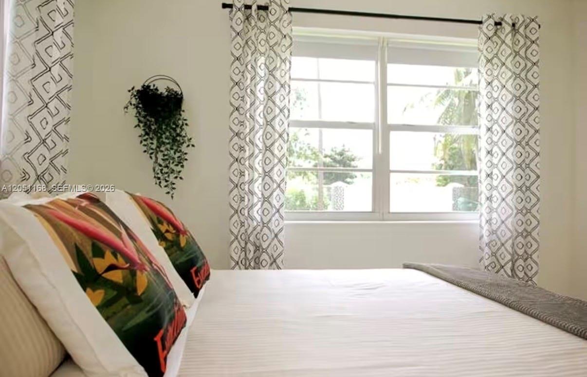 A bedroom features a bed with patterned pillows, white bedding, and curtains framing a window — 29450 SW 180th Ave, Homestead FL 33030, HOMESTEAD, FL