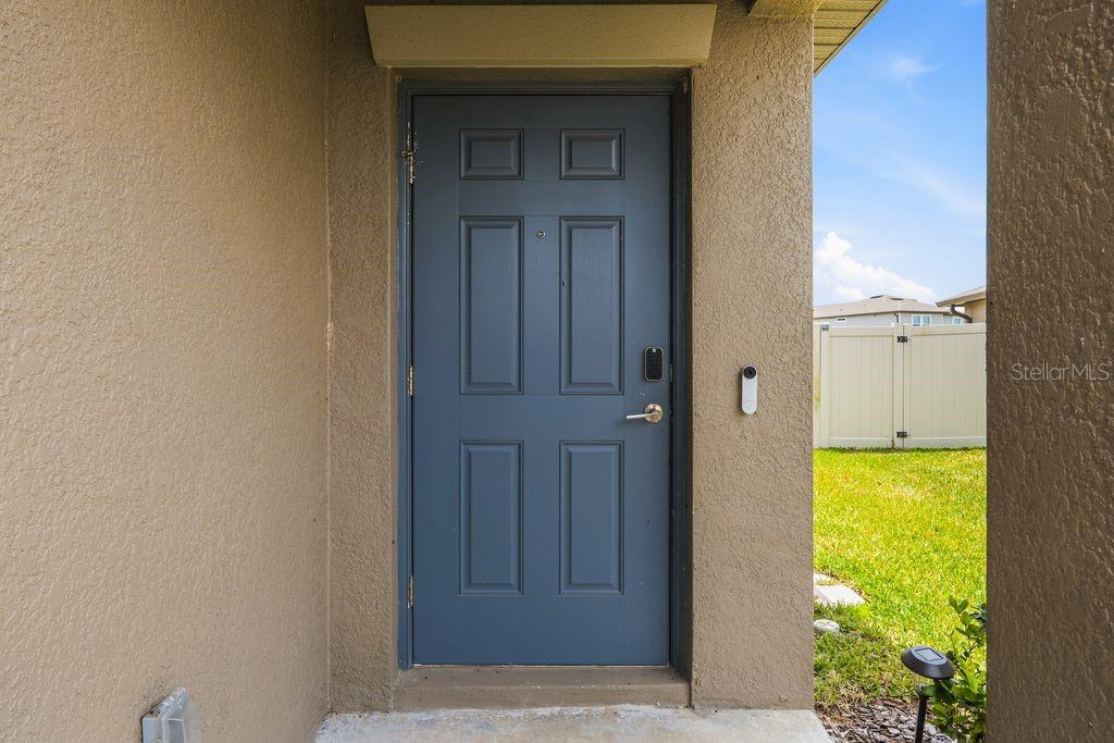 A blue six-panel front door is set within a tan stucco entryway — 9617 BRANCHING SHIP TRACE, WESLEY CHAPEL, FL