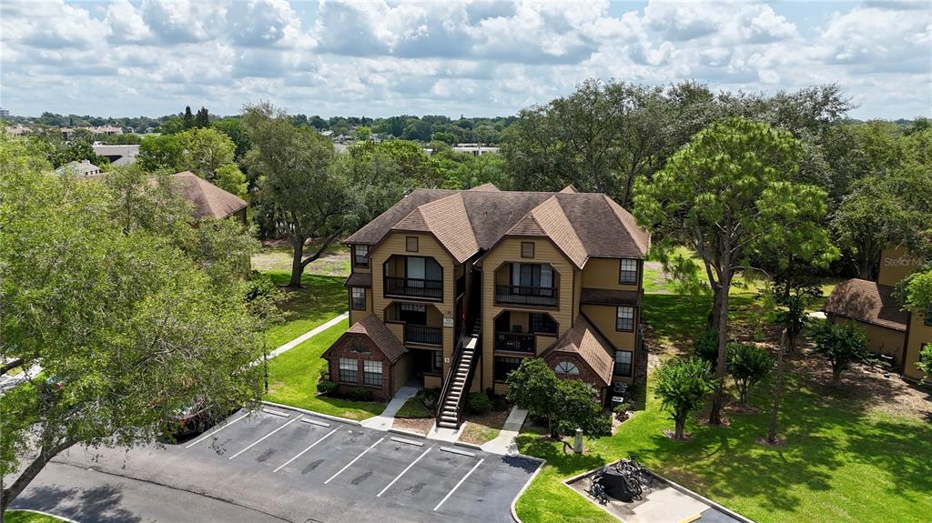 An aerial view of a multi-story apartment building with a parking lot and surrounding trees — 315 LAKEPOINTE DRIVE UNIT 101, ALTAMONTE SPRINGS, FL