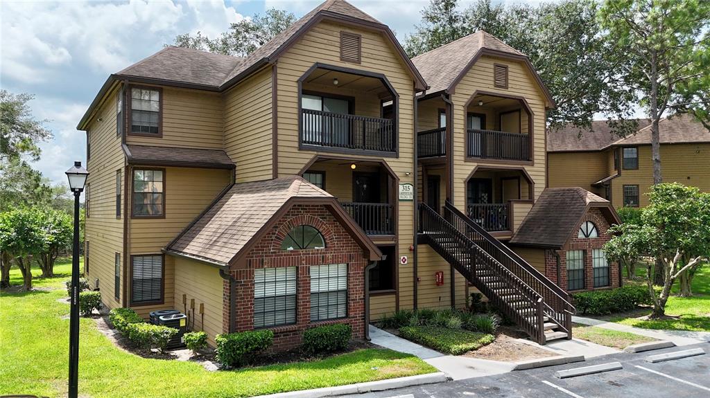 A three-story apartment building with tan siding, brick accents, and an exterior staircase — 315 LAKEPOINTE DRIVE UNIT 101, ALTAMONTE SPRINGS, FL