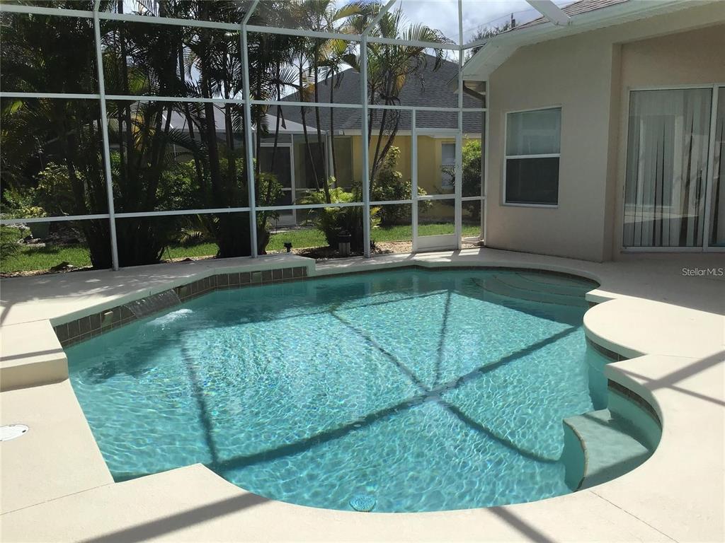 A screened-in swimming pool with a waterfall feature sits on a concrete patio — 1292 W HILLSBOROUGH BOULEVARD, NORTH PORT, FL