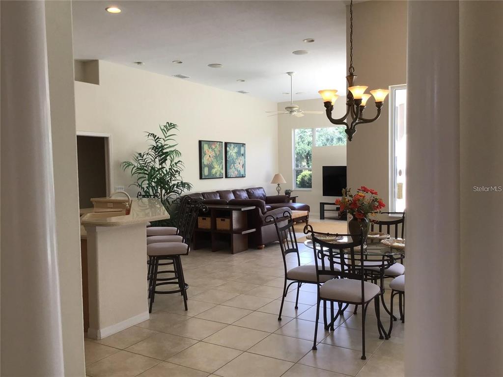 An open-concept living and dining area features tile flooring, a breakfast bar, and vaulted ceilings — 1292 W HILLSBOROUGH BOULEVARD, NORTH PORT, FL