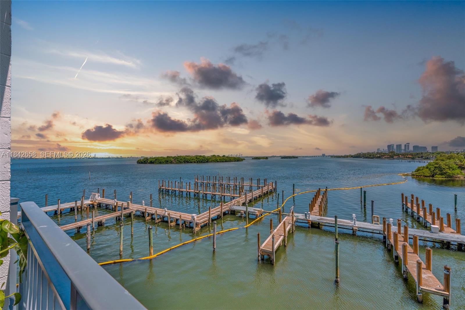 A balcony with a table and chairs overlooks a bay and a distant city skyline — 770 NE 69th St # 4H, Miami FL 33138, MIAMI, FL