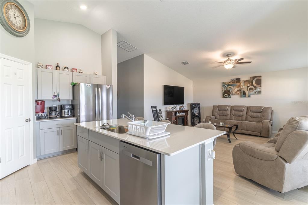A kitchen with a center island and stainless steel appliances opens into a living room — 3704 DUSTY MILLER PLACE, HAINES CITY, FL