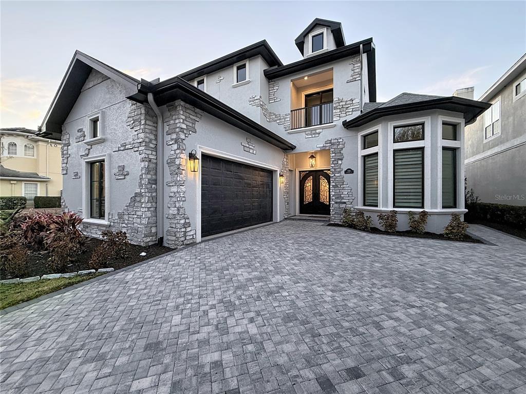 A two-story house features a stone-accented facade, a paved driveway, and a dark garage door — 7394 GATHERING COURT, REUNION, FL