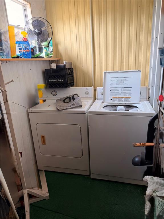 A laundry area features a white dryer and washing machine sitting on a green floor — 38533 LANSING AVENUE, ZEPHYRHILLS, FL