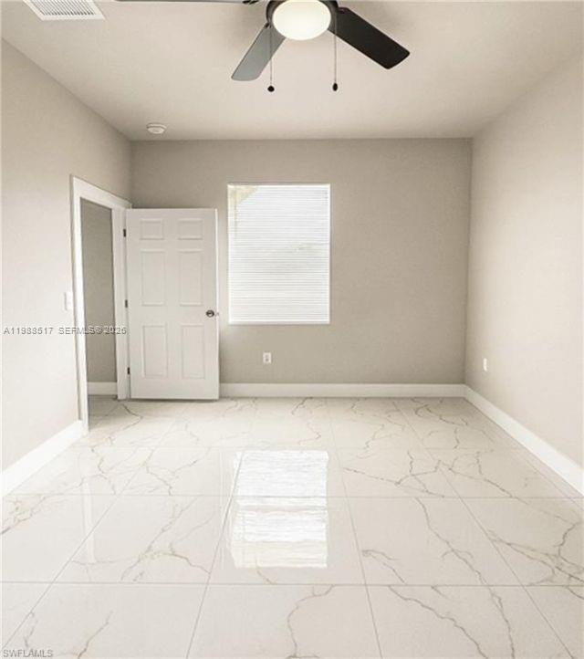 An empty room features white marble-look tile flooring, a ceiling fan, and a single window — 816 Palomino, Lehigh Acres FL 33974, LEHIGH ACRES, FL