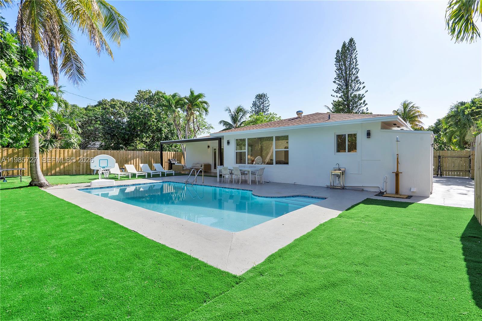 A backyard features a swimming pool, artificial turf, a patio, and a white house exterior — 10801 Peachtree Dr, Miami FL 33161, MIAMI, FL