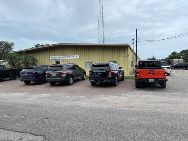A commercial building with a parking lot containing several vehicles, including a bright orange Jeep — 5654 SARAH AVENUE, SARASOTA, FL